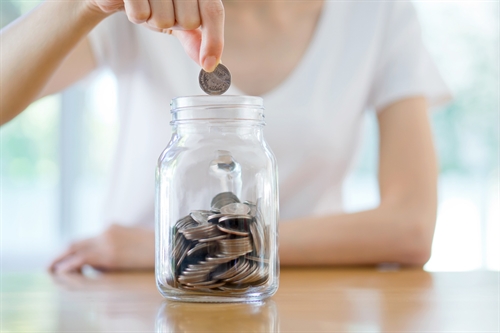 A woman filling a jar with coins she has saved by getting a good deal on her storage insurance