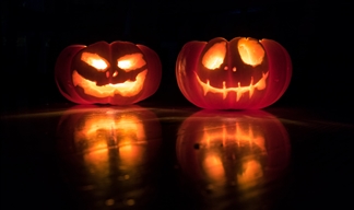 Two lit pumpkin lanterns in the dark