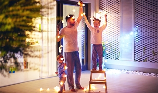 Dad and two boys taking down Christmas lights in a large modern room