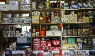 a collection of tins and vintage storage kept on cluttered shelves with a window behind. a collection of tins and vintage storage kept on cluttered shelves with a window behind.